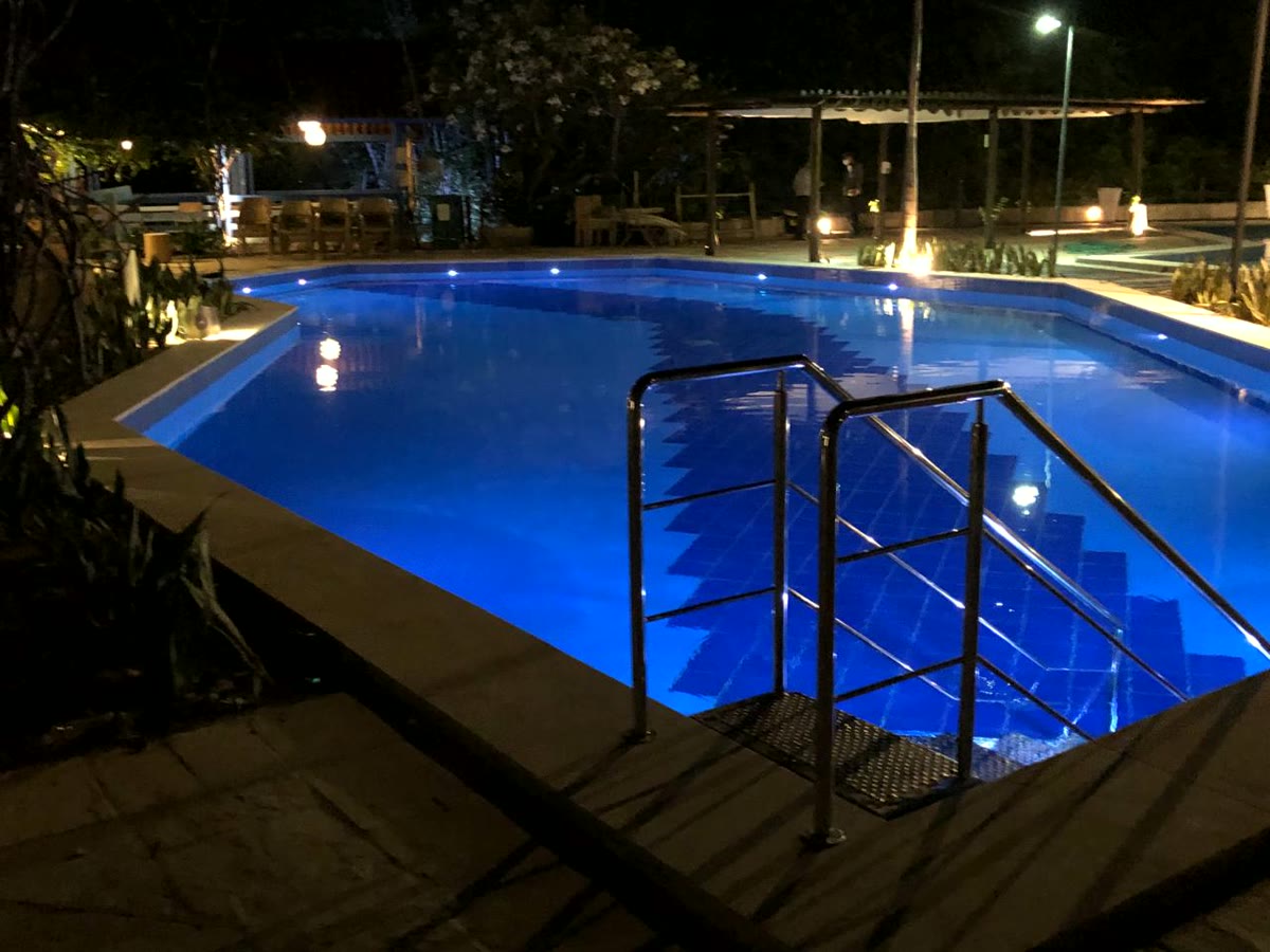 Piscina iluminada à noite, com escada de acesso